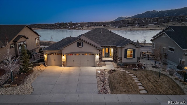 french country style house featuring stucco siding, concrete driveway, a mountain view, a garage, and stone siding