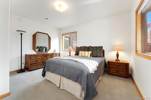 bedroom with light carpet, baseboards, and multiple windows