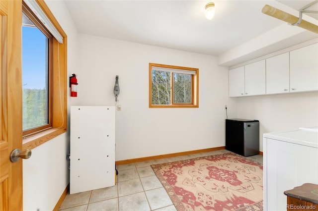 washroom with cabinet space, washer / clothes dryer, baseboards, and light tile patterned flooring
