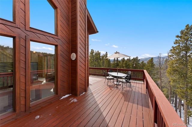 wooden terrace featuring a mountain view and outdoor dining area