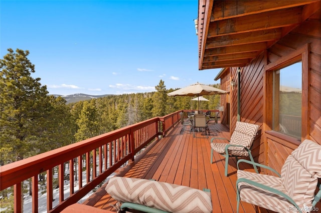 wooden deck with outdoor dining space and a forest view