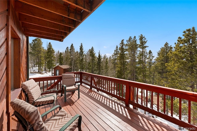 wooden deck with a forest view and an outbuilding