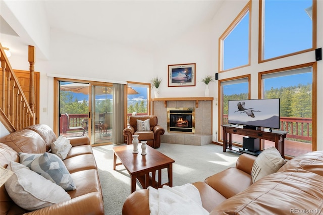 carpeted living room with high vaulted ceiling, a fireplace, and stairway