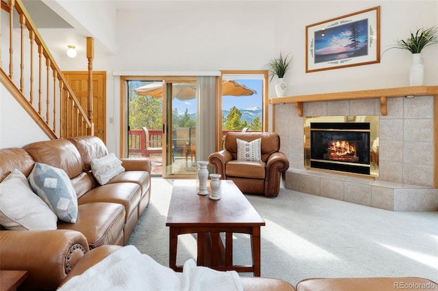 living room featuring a fireplace, stairs, and carpet floors