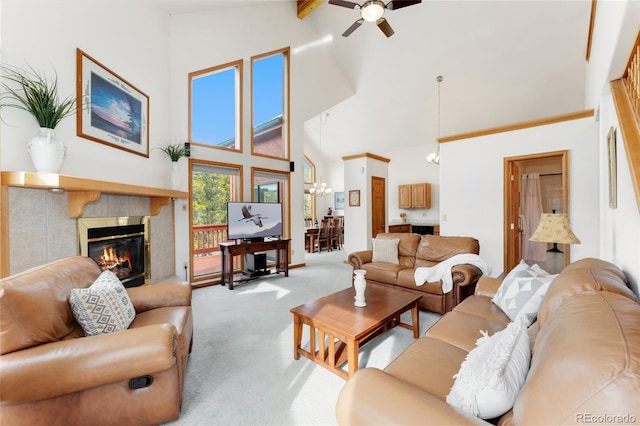living room featuring high vaulted ceiling, carpet flooring, a tiled fireplace, and ceiling fan with notable chandelier