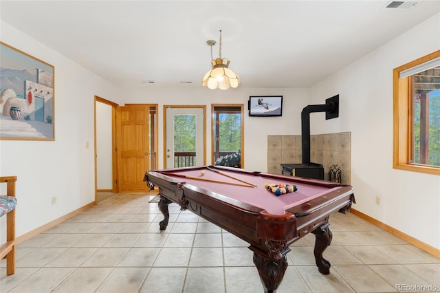 game room featuring visible vents, light tile patterned floors, a wood stove, and baseboards