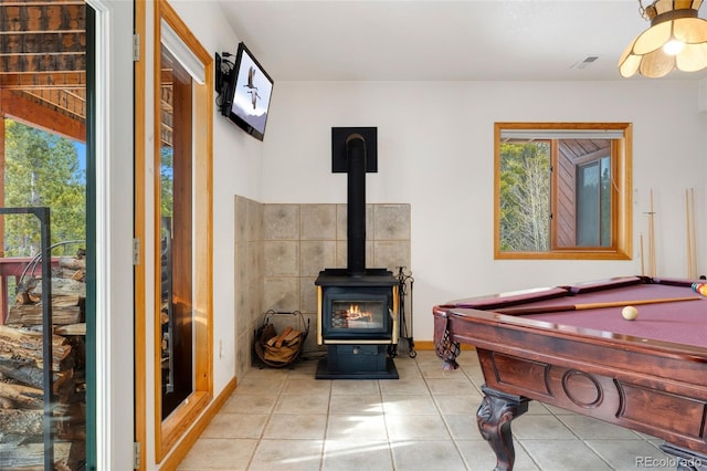 recreation room with tile patterned floors, a wood stove, billiards, and a wealth of natural light
