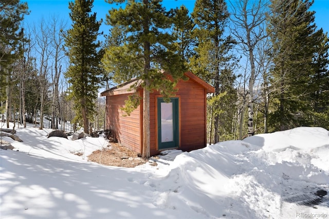 snow covered structure with an outbuilding