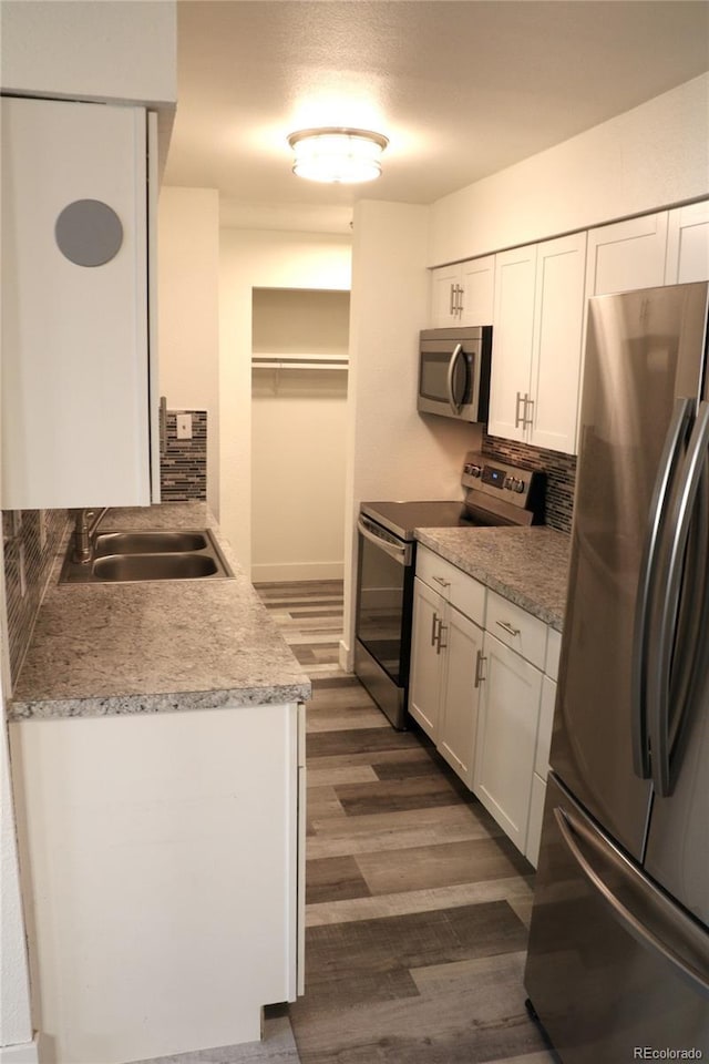 kitchen featuring white cabinetry, sink, dark wood-type flooring, tasteful backsplash, and appliances with stainless steel finishes