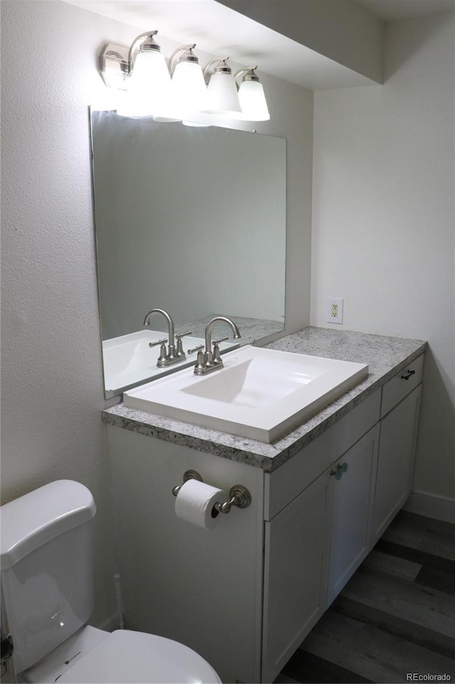 bathroom with hardwood / wood-style floors, vanity, and toilet