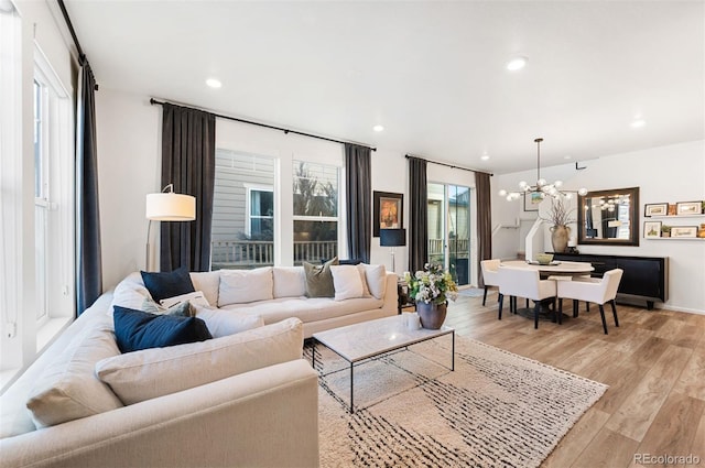 living room featuring light wood-style flooring, a notable chandelier, and recessed lighting