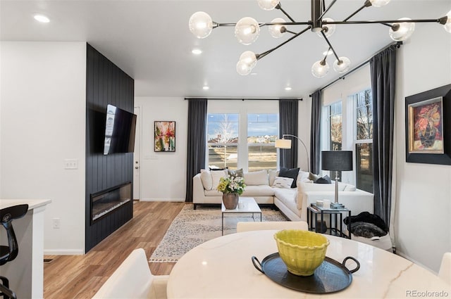 living area with baseboards, light wood finished floors, and recessed lighting