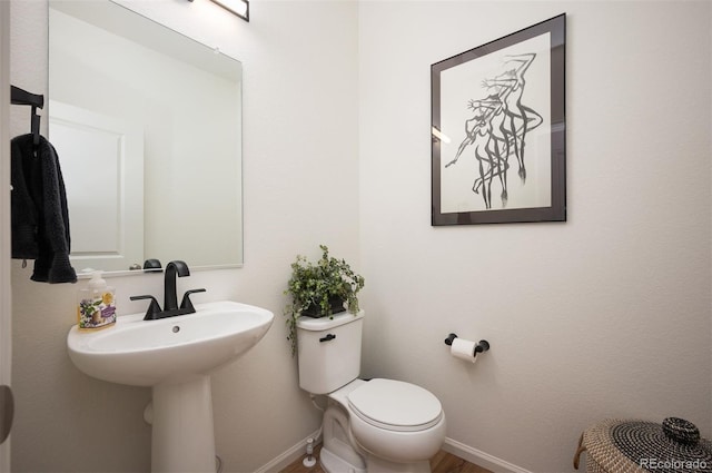 bathroom featuring baseboards, a sink, and toilet