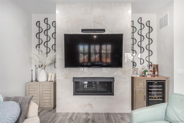 living room with wood finished floors, a bar, a fireplace, visible vents, and wine cooler
