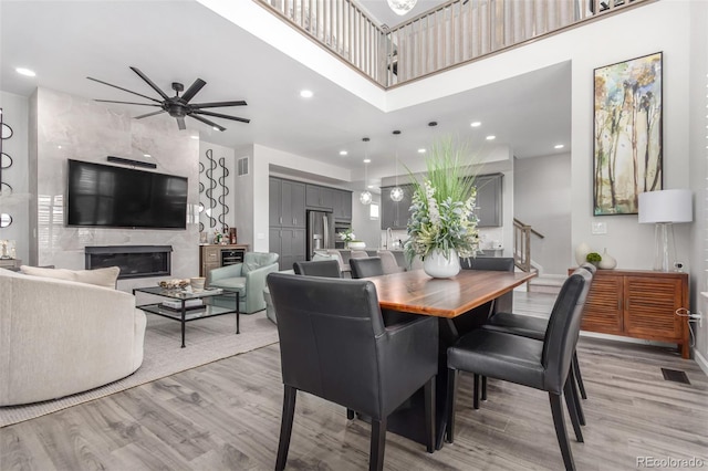 10524 Eby Cir, Lone Tree, CO 80124 - dining room with light wood-type flooring, a ceiling fan, a high end fireplace, recessed lighting, and a high ceiling