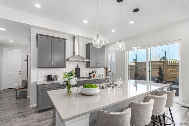 10524 Eby Cir, Lone Tree, CO 80124 - kitchen with wall chimney range hood, gray cabinetry, a breakfast bar area, decorative backsplash, and recessed lighting
