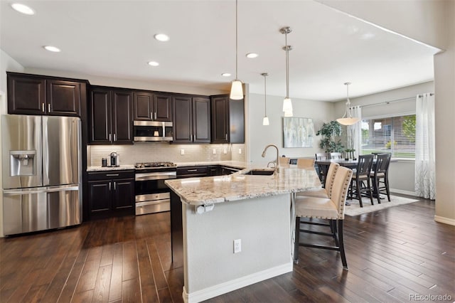 335 Mountain Brush, Colorado Springs, CO 80921 - kitchen with stainless steel appliances, a breakfast bar, dark wood-style flooring, tasteful backsplash, and recessed lighting