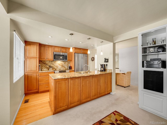 1011 N Pennsylvania St Unit H, Denver, CO 80203 - kitchen featuring appliances with stainless steel finishes, a peninsula, light stone countertops, pendant lighting, and tasteful backsplash
