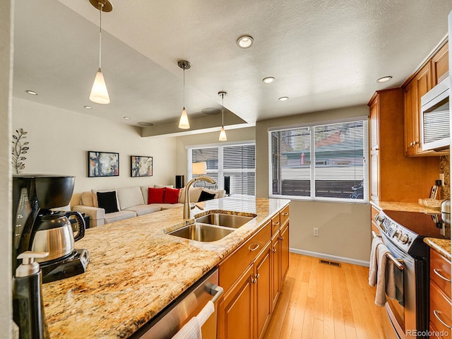 1011 N Pennsylvania St Unit H, Denver, CO 80203 - kitchen with stainless steel appliances, a sink, brown cabinetry, light wood-style floors, and recessed lighting