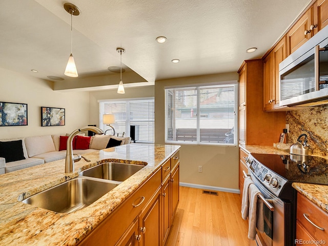 1011 N Pennsylvania St Unit H, Denver, CO 80203 - kitchen featuring stainless steel appliances, brown cabinets, a sink, light wood-style flooring, and recessed lighting