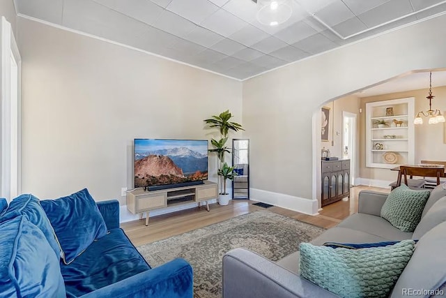 living area featuring light wood-style floors, ornamental molding, and arched walkways