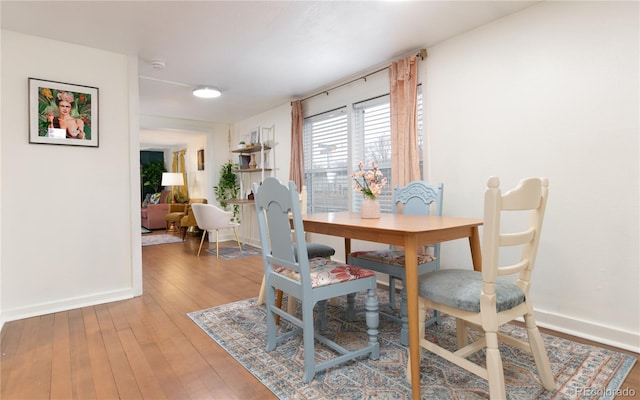 dining space featuring wood-type flooring and baseboards