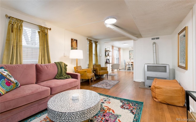 living area with wood-type flooring, heating unit, and visible vents