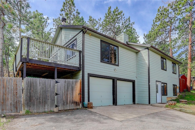 view of property exterior with fence, aphalt driveway, a garage, a deck, and a chimney