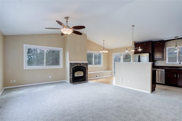 unfurnished living room with a sink, ceiling fan with notable chandelier, vaulted ceiling, and light carpet
