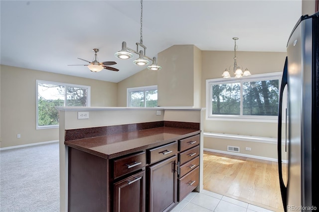 kitchen with hanging light fixtures, ceiling fan with notable chandelier, freestanding refrigerator, lofted ceiling, and visible vents