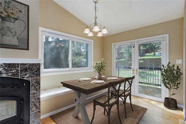 dining space with a notable chandelier, a healthy amount of sunlight, lofted ceiling, and light wood-type flooring