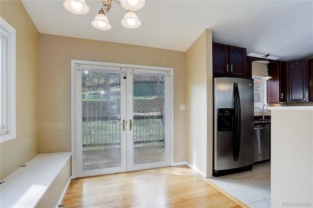 kitchen featuring an inviting chandelier, light wood-style floors, french doors, a sink, and appliances with stainless steel finishes