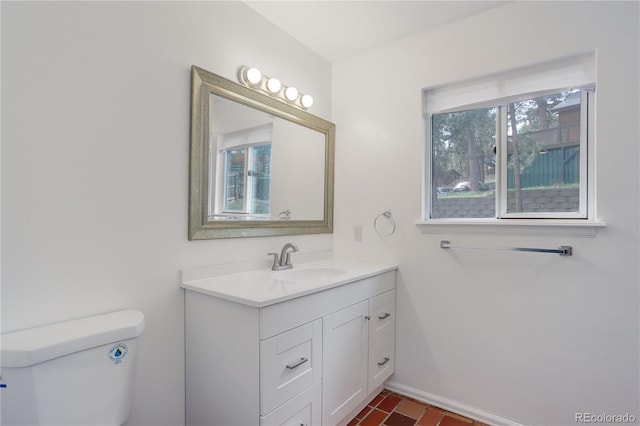 half bathroom featuring vanity, baseboards, and toilet