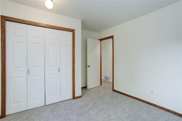 unfurnished bedroom with baseboards, visible vents, light carpet, and a closet