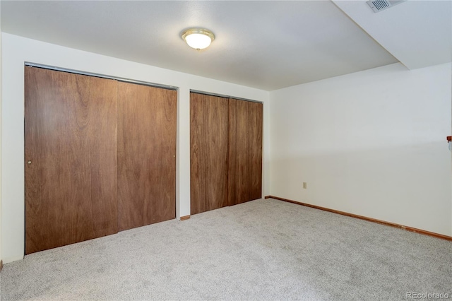 unfurnished bedroom with visible vents, carpet flooring, multiple closets, and baseboards