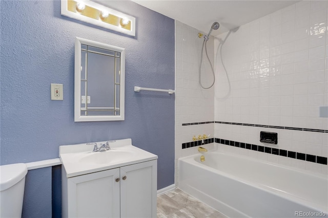 full bathroom featuring vanity, baseboards, toilet, a textured wall, and tub / shower combination
