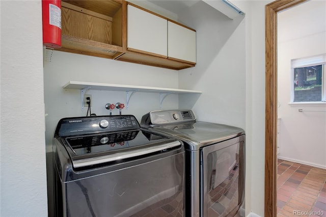 clothes washing area featuring baseboards, washer and clothes dryer, and cabinet space