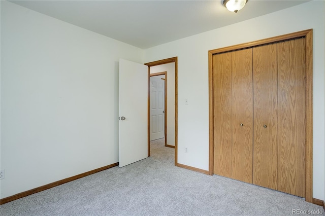unfurnished bedroom with light colored carpet, baseboards, and a closet