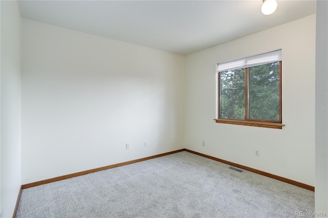 carpeted empty room featuring baseboards and visible vents