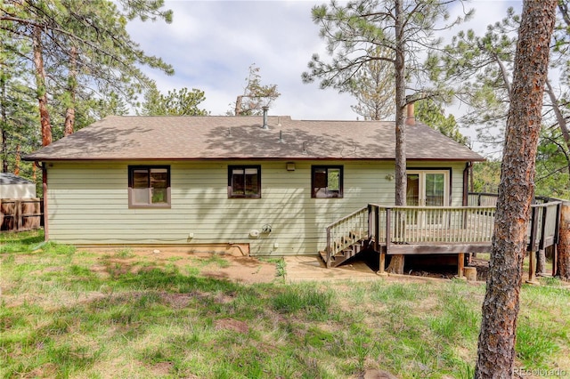 rear view of house with a deck, fence, a chimney, and a shingled roof