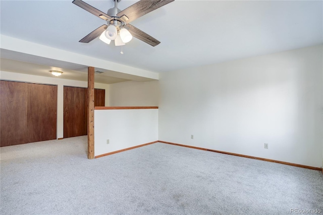 carpeted spare room featuring baseboards and ceiling fan