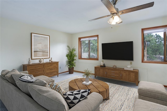 carpeted living area with baseboards and a ceiling fan