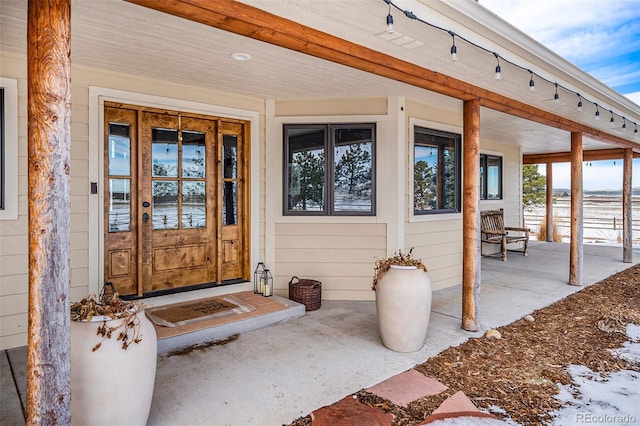 snow covered property entrance with covered porch