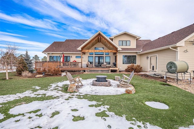 back of house with a wooden deck, an outdoor fire pit, and a lawn