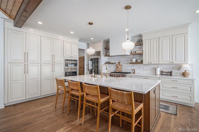 kitchen featuring a breakfast bar area, white cabinetry, hanging light fixtures, dark hardwood / wood-style floors, and a center island with sink