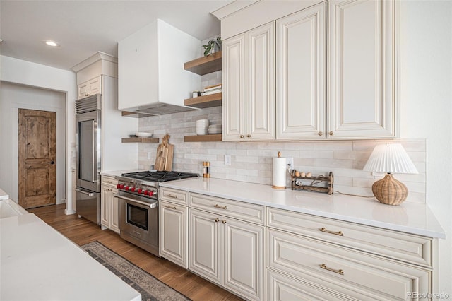 kitchen with white cabinets, high quality appliances, hardwood / wood-style floors, and wall chimney range hood