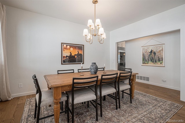 dining space with dark hardwood / wood-style flooring and a notable chandelier