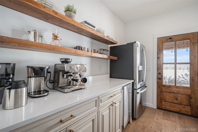 kitchen with white cabinets, stainless steel fridge with ice dispenser, and light wood-type flooring