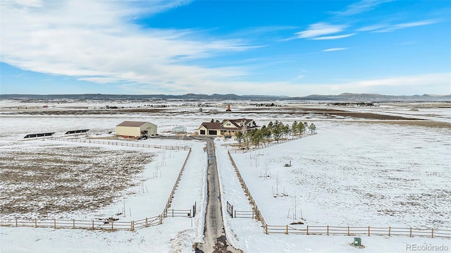 snowy aerial view featuring a mountain view and a rural view