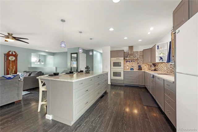 kitchen with a kitchen island, a kitchen breakfast bar, white refrigerator, backsplash, and double wall oven